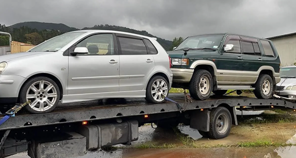 Tow truck transporting two scrap cars in Wellington.